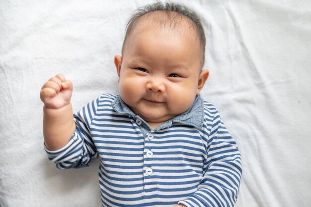 Baby lying face up on a white bed