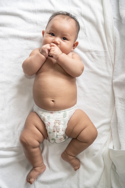 Baby lying face up on a white bed