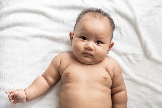 Baby lying face up on a white bed