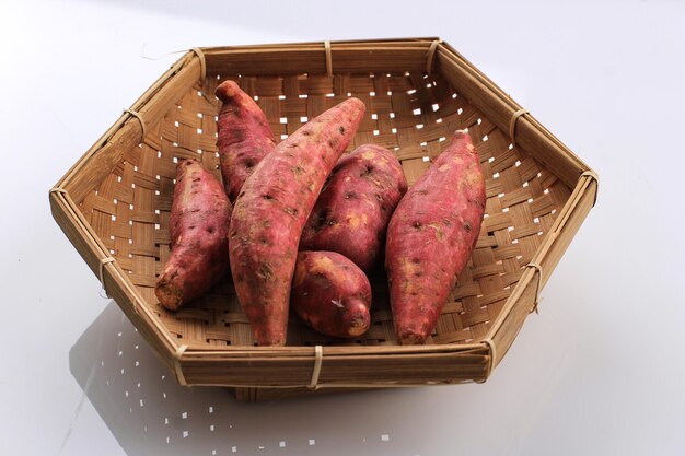 Baby mini red sweet potato на бамбуковой тарелке wooven basket. изолированные на белом фоне. копировать пространство для текста