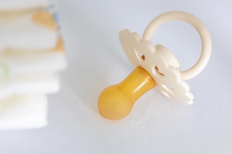 Free Photo baby pacifier and diapers in the crib closeup