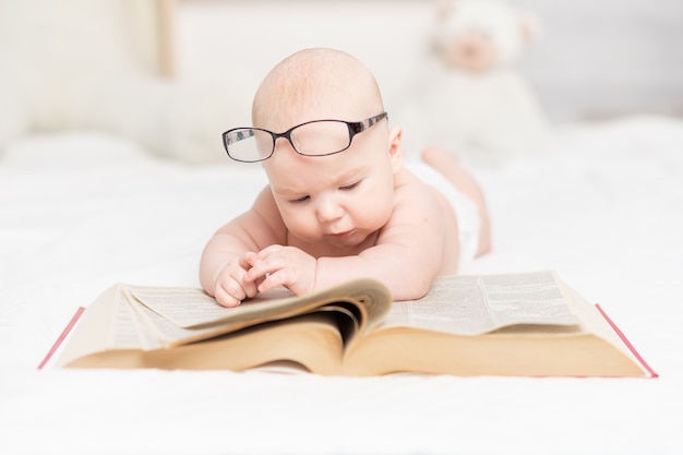 Premium Photo Baby Reading A Book Or Looking At It In The Nursery Learning And Development Concept Premium Photo Baby Reading A Book Or Looking At It In The Nursery Learning And Development Concept
