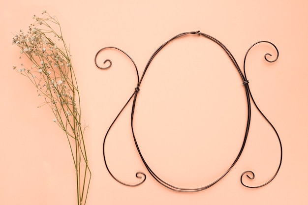 Baby's breath flowers near the empty oval frame on peach colored backdrop