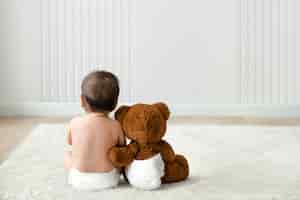 Free photo baby and teddy bear rear view with design space