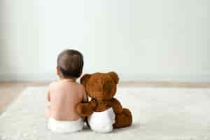 Free photo baby and teddy bear rear view with design space