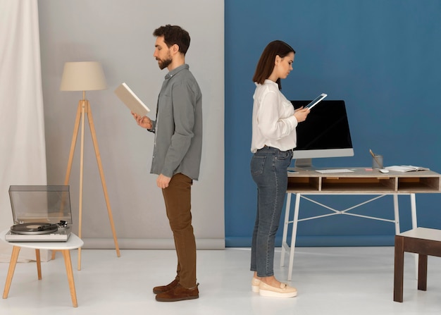 Back to back man with book and woman with tablet