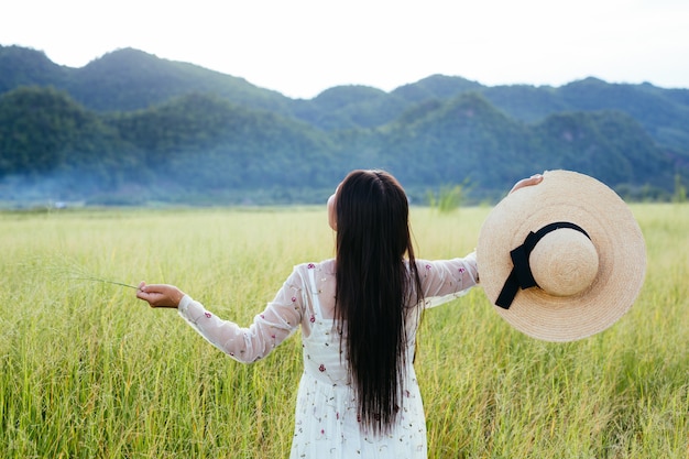 大きな山のある牧草地で幸せな美しい女性の背中。