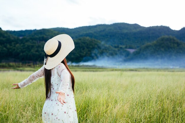 大きな山のある牧草地で幸せな美しい女性の背中。