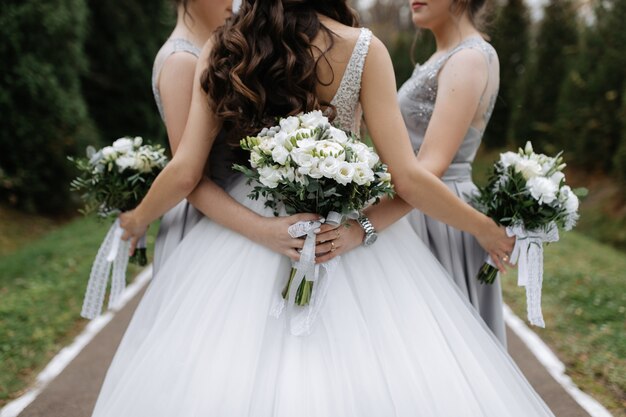 Спинка невесты и подружки невесты с белыми эустомами, свадебные букеты на природе