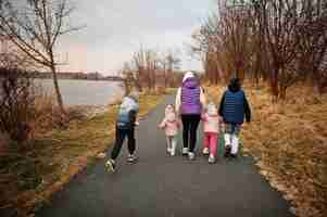 Free photo back of mother walking with kids on the path by the lake