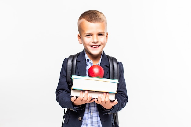 Di nuovo a scuola. libri, mela, scuola, ragazzo. il piccolo studente tiene i libri. piccolo bambino sorridente allegro contro la lavagna. concetto di scuola