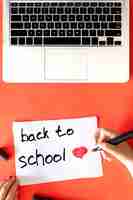 Free photo back to school the childs hand writes in a paper on a red background