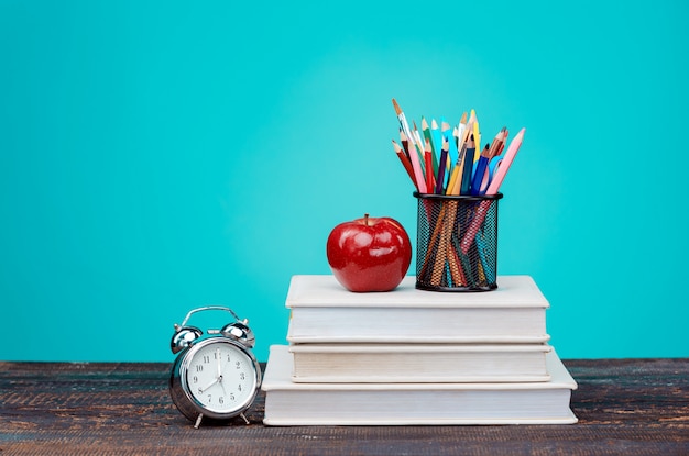 Back to School concept. Books, colored pencils and clock