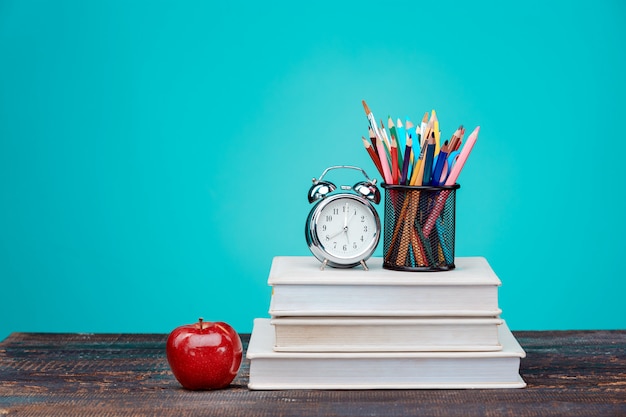 Back to School concept. Books, colored pencils and clock