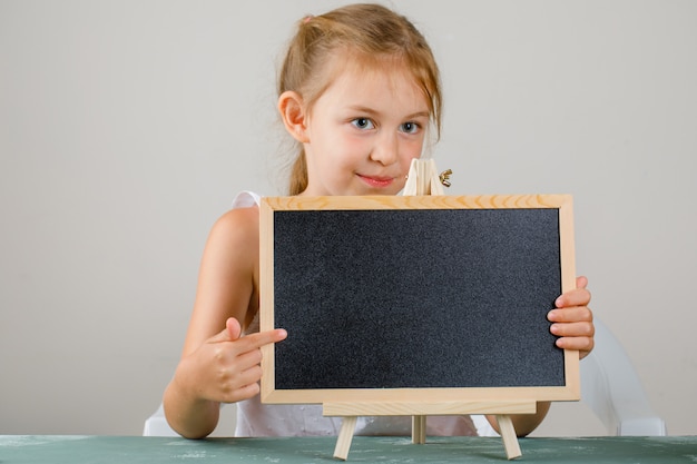 学校のコンセプトに戻る側面図。小さな女の子を保持し、黒板を示します。