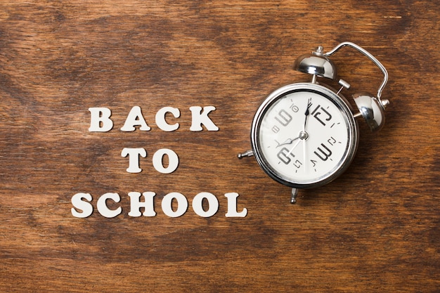 Free photo back to school concept with clock on wooden background