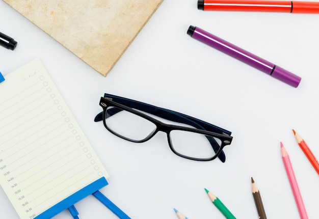 Back to school concept with glasses, school supplies, daily planner on white table flat lay.