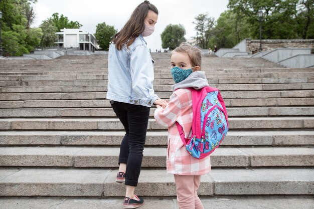 学校に戻る。コロナウイルスのパンデミックの子供たちはマスクをして学校に行きます。母との友好関係。