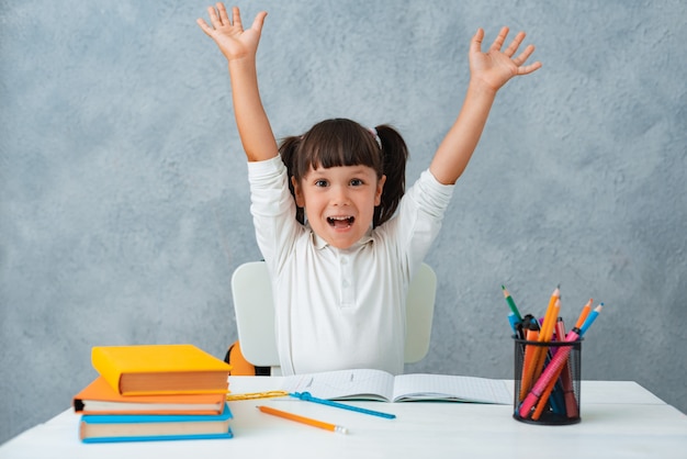 Back to school. Cute child schoolgirl sitting at a Desk in the room.