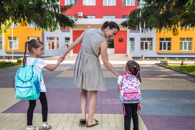 Back to school education concept with girl kids, elementary students, carrying backpacks going to class