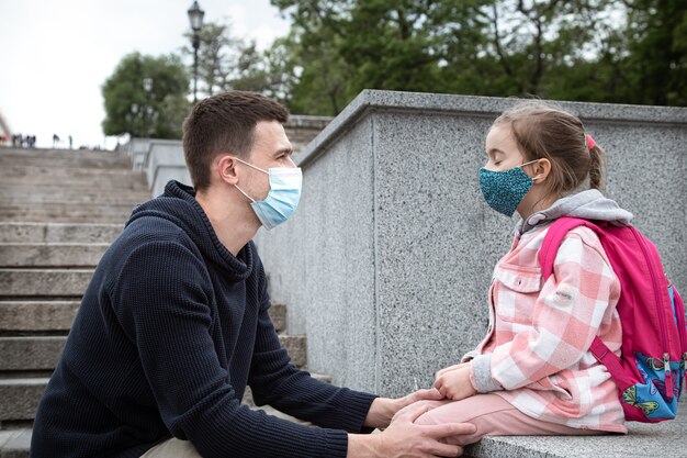 Back to school, pandemic. Young father and little daughter in a mask. Friendly family relationships.