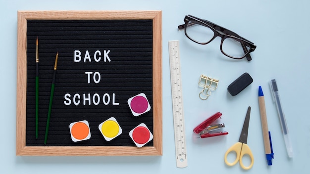 Free photo back to school text on slate with colorful watercolor paints and paintbrush near various stationeries