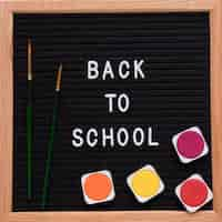 Free photo back to school text on slate with colorful watercolor paints and paintbrush