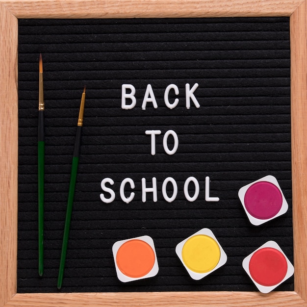 Back to school text on slate with colorful watercolor paints and paintbrush
