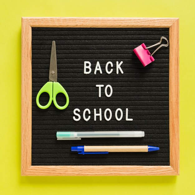 Back to school text on slate with stationeries over yellow backdrop