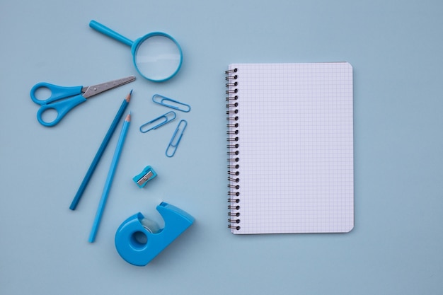 back to school with empty notebook for mock up scissors, magnifying glass  on light blue 