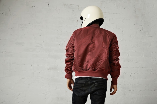 Free photo back shot of a motorcyclist in white helmet and burgundy bomber jacket isolated on white