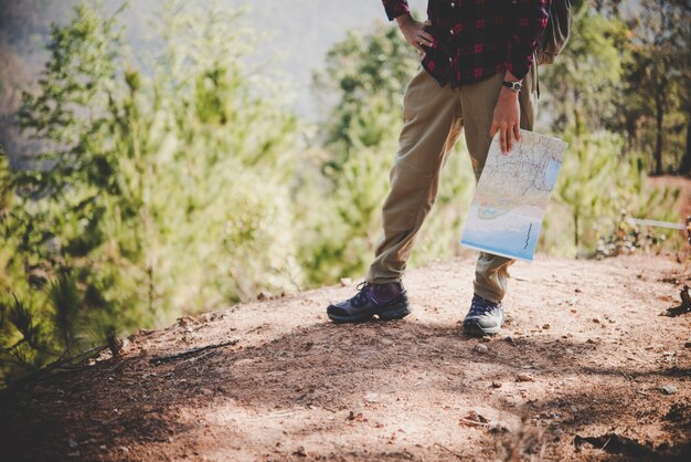 Back side of traveler girl searching right direction on map, while traveling to hiking in the mountain. Travel concept.