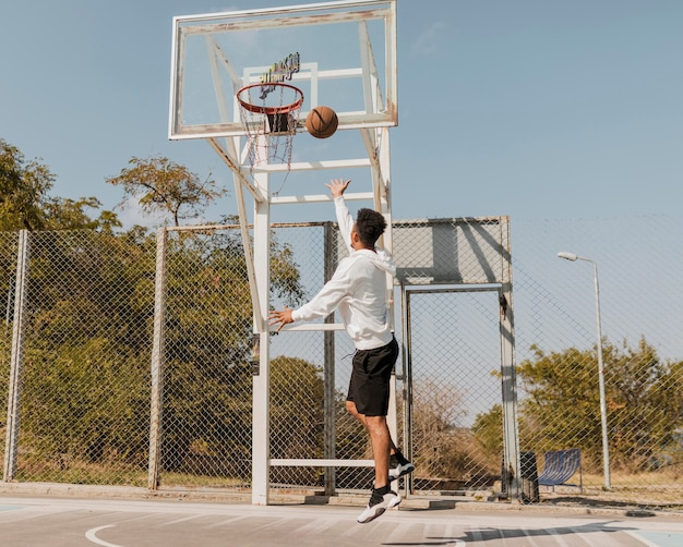 Back view african american man playing with a basketball