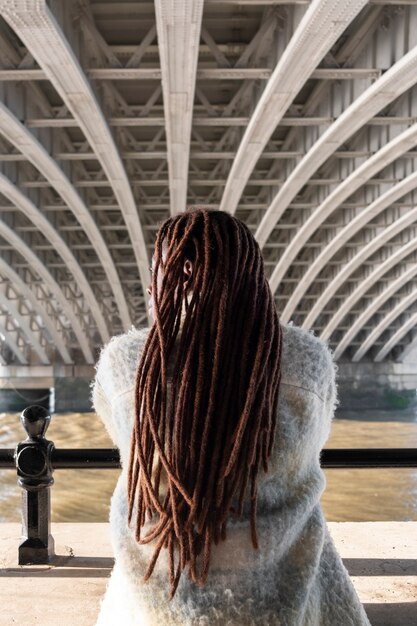 Вид сзади на афро-дреды на женщине, позирующей на улице под мостом