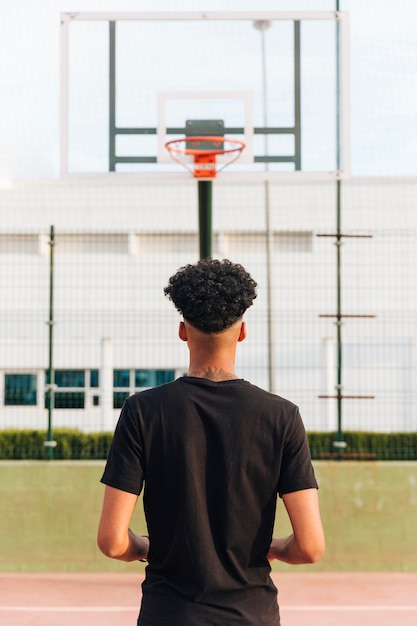 Free photo back view of athletic anonymous male at basketball court