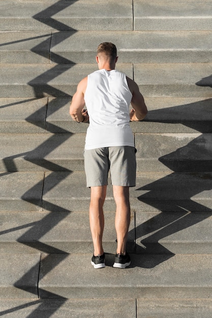 Back view athletic man doing push ups on stairs