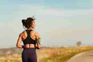 Free photo back view of athletic woman jogging while exercising in nature copy space