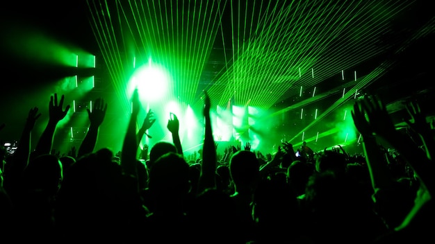 Back view of audience with arms raised in front of stage at music concert