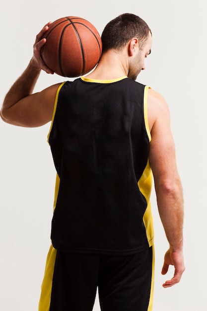 Free photo back view of basketball player holding ball on shoulder