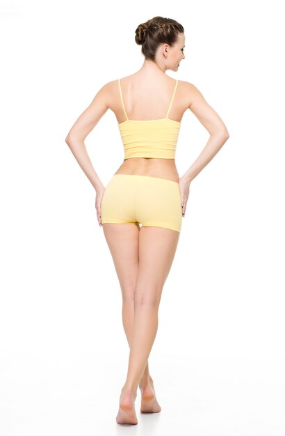 Back view of a beautiful sporty female body in yellow underwear posing isolated on white wall