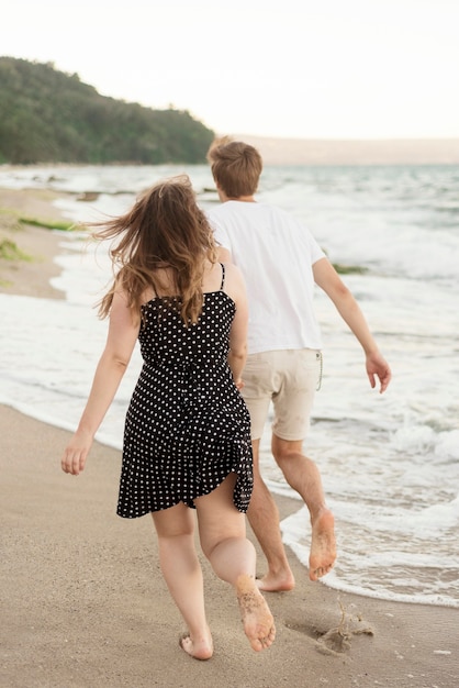 Free photo back view boy and girl taking a walk together on the beach