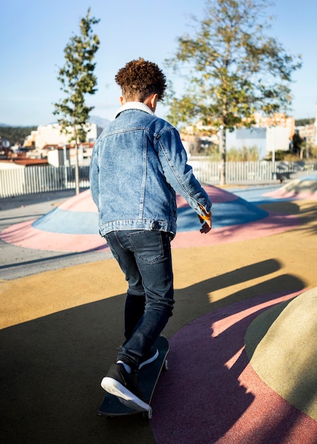 Free photo back view boy skateboarding at the park