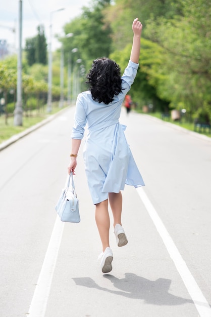 Back view brunette girl in light blue dress