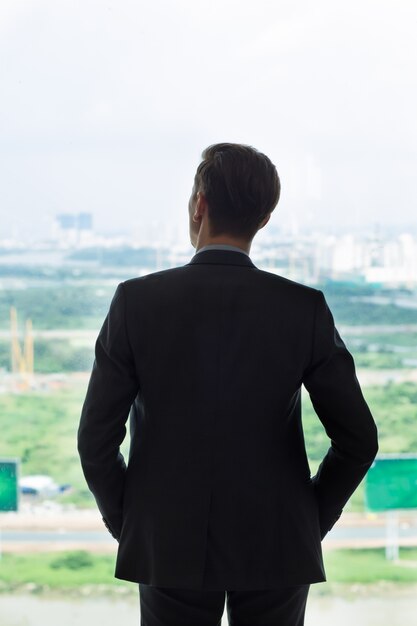 Back View of Businessman Looking at City in Window