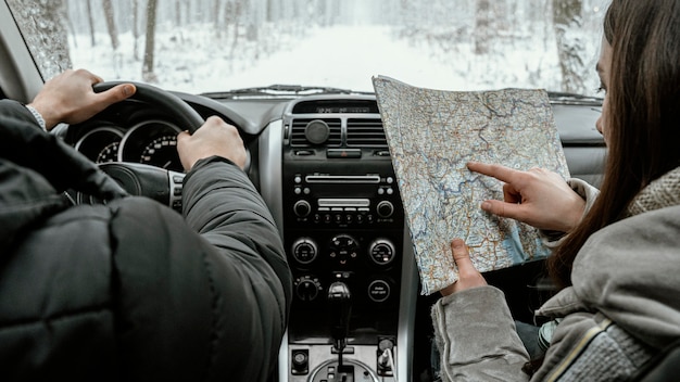 Foto gratuita vista posteriore della coppia in macchina durante un viaggio su strada consultando la mappa