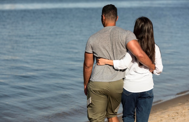 Back view of couple holding each other at the beach