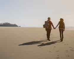 Free photo back view of couple holding hands on beach