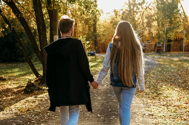 Back view of couple holding hands in the park