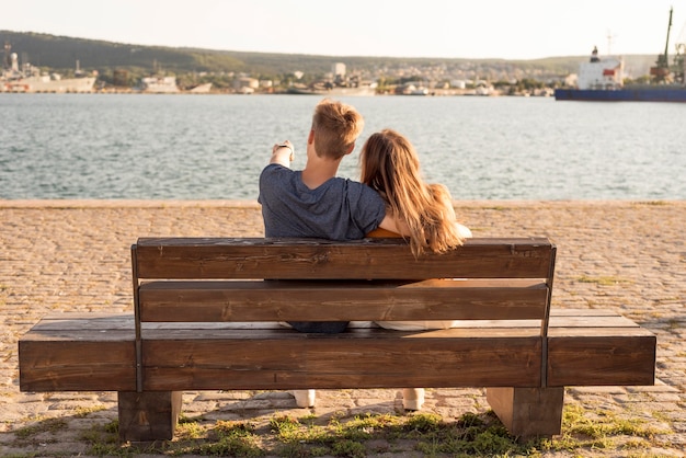 Free photo back view couple sitting on a bench