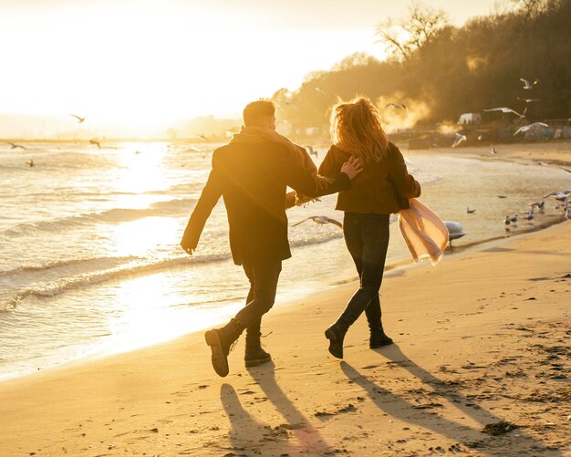 Back view of couple walking on the beach in winter